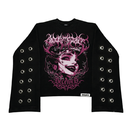 A black long-sleeve crop top sweatshirt featuring a large pink and white graphic print on the front with the words 'MADNESS' and 'DECEIVED'. The sleeves have double rows of silver metal grommets, and a small white 'Delusion' brand label is visible near the bottom hem.