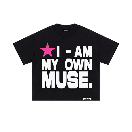 A black short-sleeve graphic t-shirt with the text 'I - AM MY OWN MUSE.' in bold white letters and a pink star graphic, shown flat on a white background.